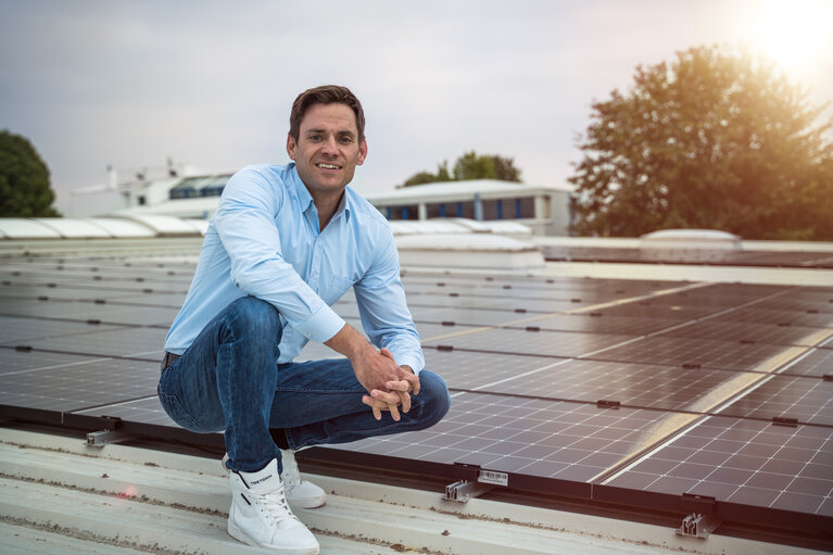 Ein Mann sitzt auf einem Dach mit Solarplatten.