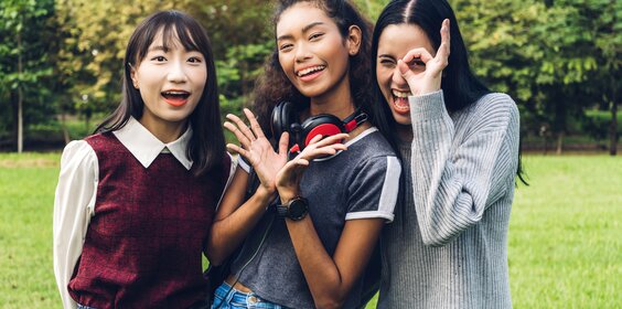 Drei Frauen stehen lachend beieinander.