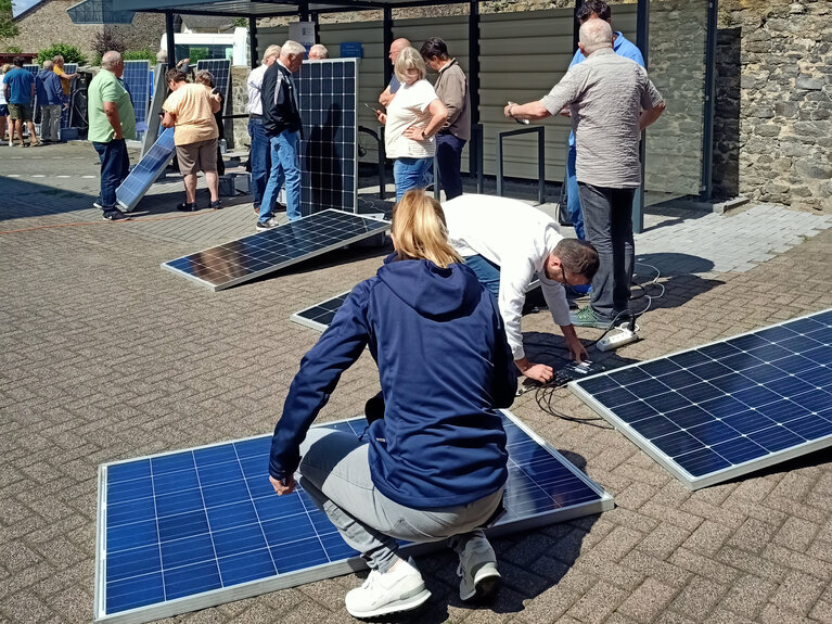 Teilnehmer des Balkonkraftwerksworkshops machen sich mit Solarpanelen vertraut