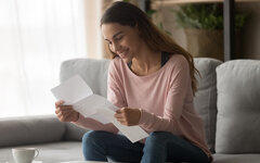 Happy woman read letter with loan approval sit on sofa