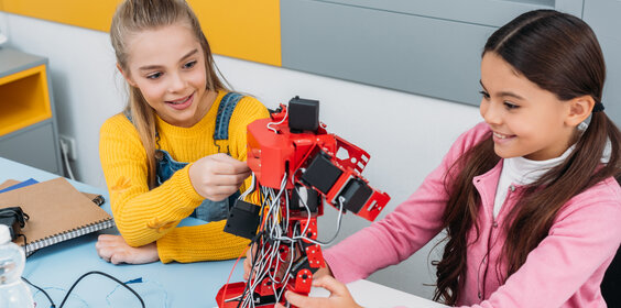 Zwei Mädchen experimentieren mit einem Roboter