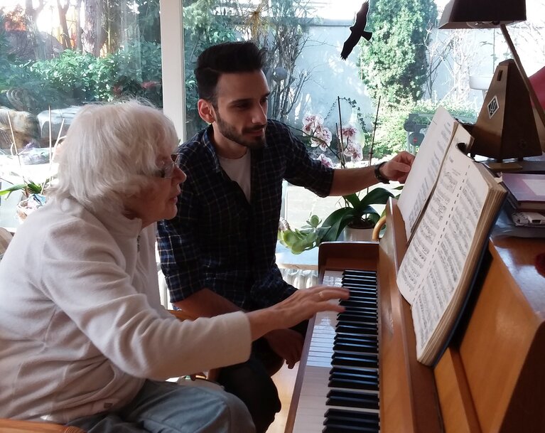 Seniorin mit Student gemeinsam am Klavier