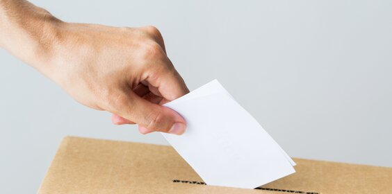 man putting his vote into ballot box on election