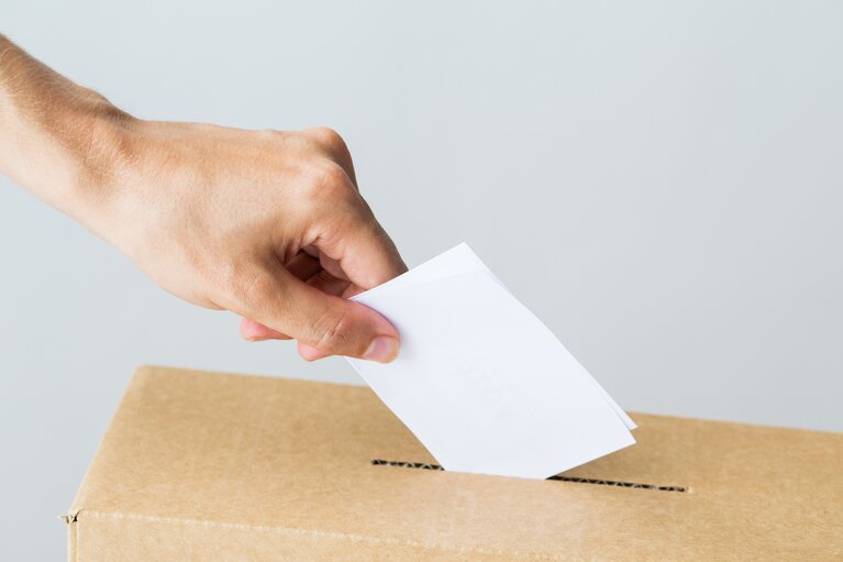 man putting his vote into ballot box on election