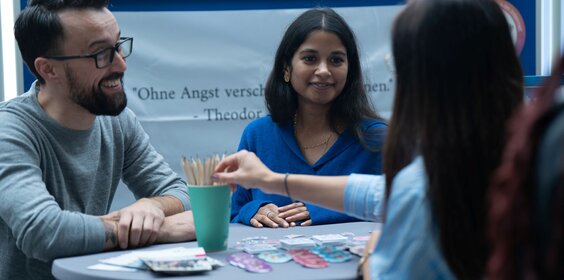 Eine Gruppe von 3-4 Personen steht an einem Projektstand.