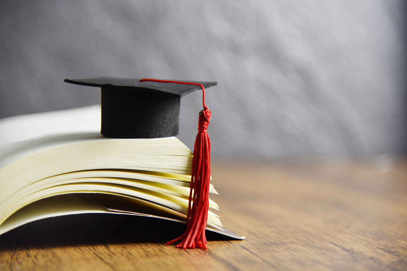 Education concept with graduation cap on a book on the wooden table 